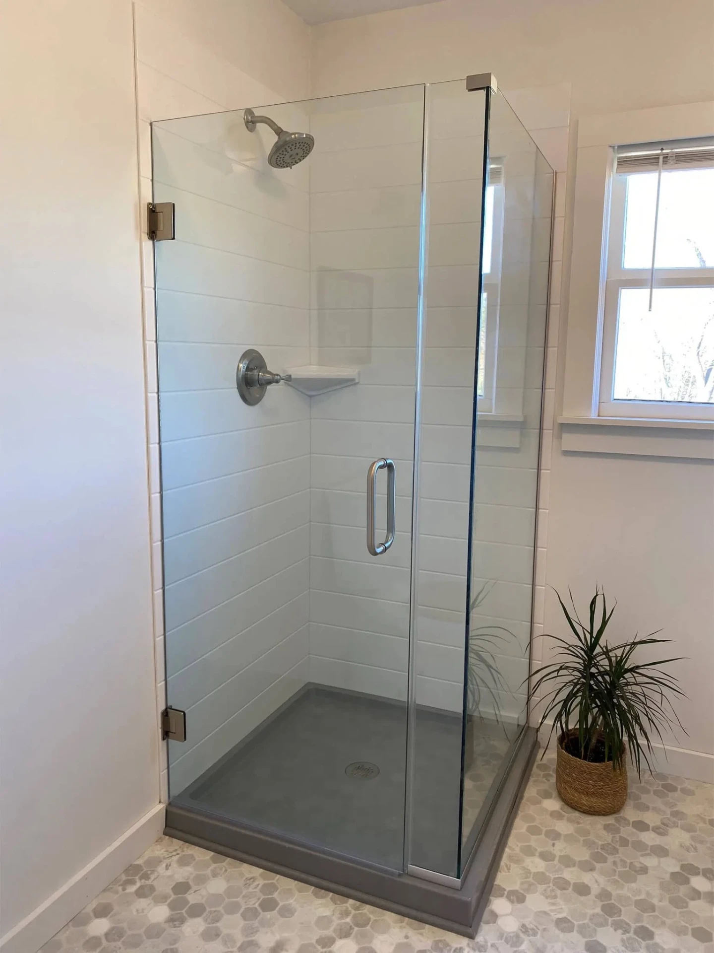 Modern shiplap-tile corner shower with frameless glass door, brushed-nickel fixtures and gray solid-surface pan