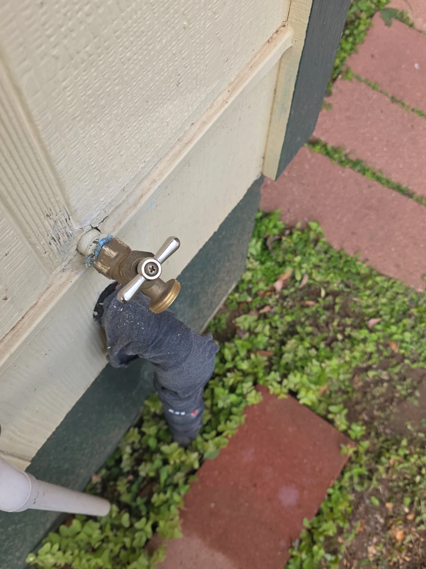Newly replaced brass outdoor hose bib spigot freshly soldered to the home's exterior wall