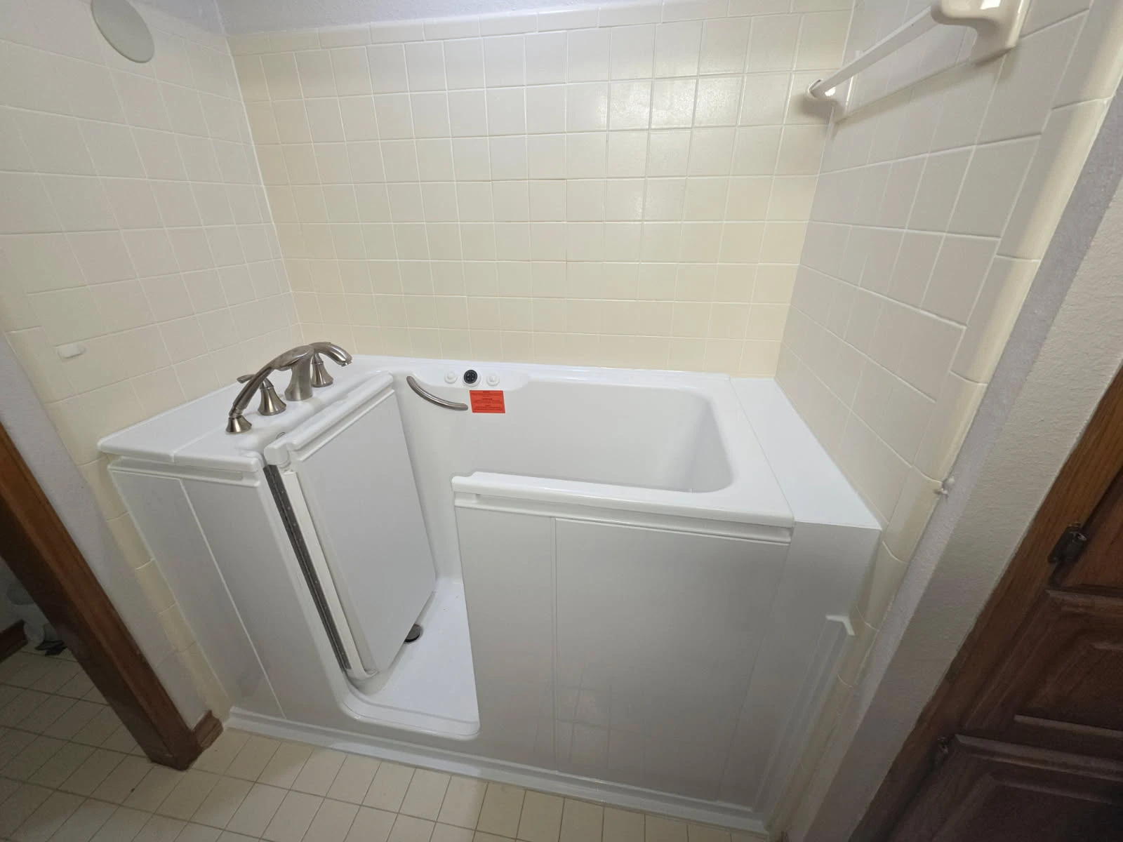 White step-in walk-in tub with inward-swing door, brushed-nickel widespread faucet and built-in grab bar — safe-bathing conversion in a San Antonio home